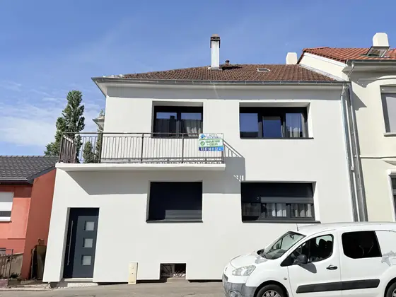 La même maison après isolation et crépi : façade blanche unie, menuiseries anthracite